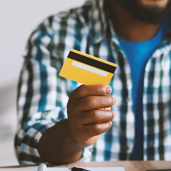 Close up shot of a person holding a yellow credit card