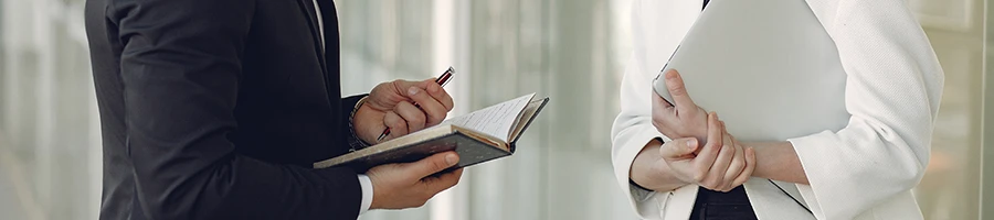 An image of two people having a conversation while holding paperworks