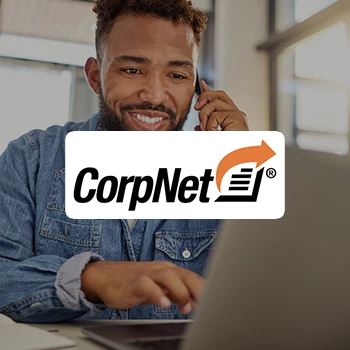 A man taking a call while using a laptop and a logo of CorpNet LLC