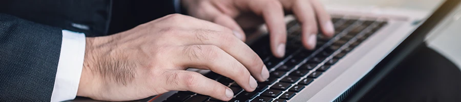 A close up shot of a business man writing his user testimonial using a laptop