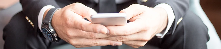 A close up shot of a businessman sitting while reading other user testimonials on a smartphone