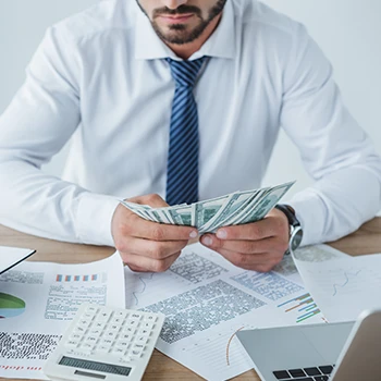 A business man counting money on his office desk