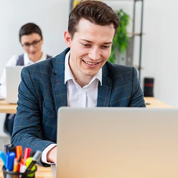 A smiling business man using a laptop in an office