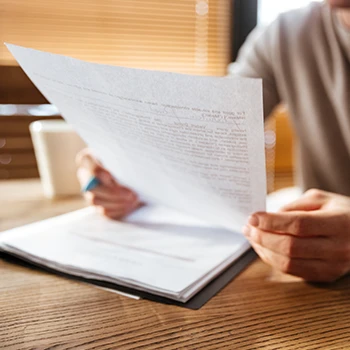 A man reading certified document copies on his desk