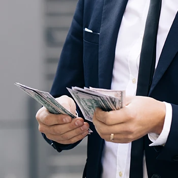 A close up shot of a business man counting dollars in his hand