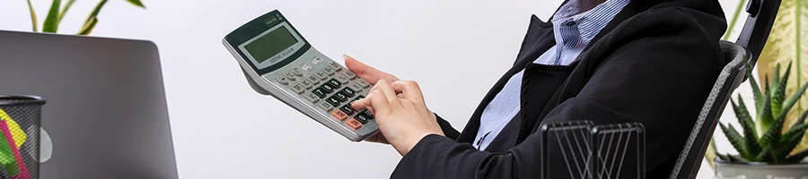 A woman holding a calculator computing the cost of an LLC in Hawaii