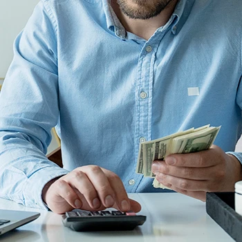 A business man holding money while calculating LLC taxes