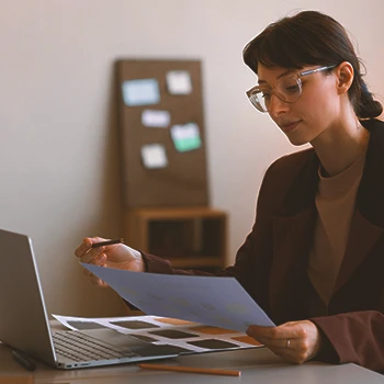 An office worker looking at paperwork in front of a laptop