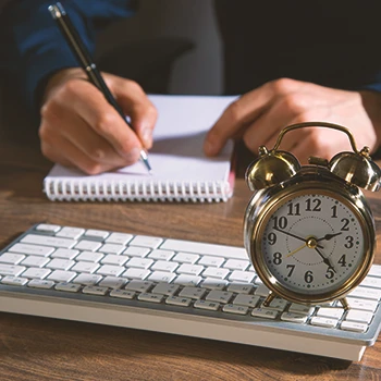 A person working in an office with a clock on the table