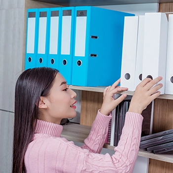 A woman organizing files on a cabinet