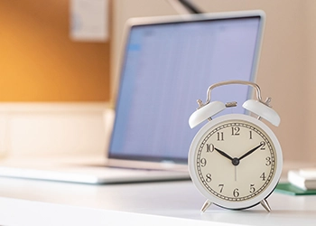 A clock beside a laptop in Oklahoma office