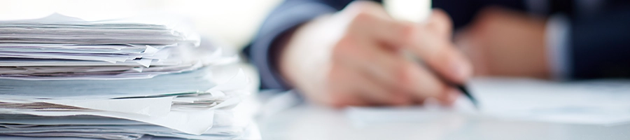 Writing on a document, camera focused on a stack of files