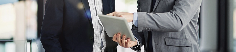 Businessmen discussing over a tablet device about filing LLC state taxes in Colorado