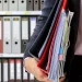 Holding a stack of document inside a folder about LLC annual report in Washington